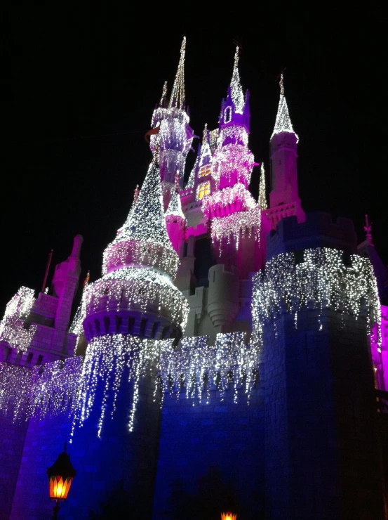 a castle lit up with fairy lights at night, inspired by disney, (1 as december, pink magic, blog-photo, greg simkins