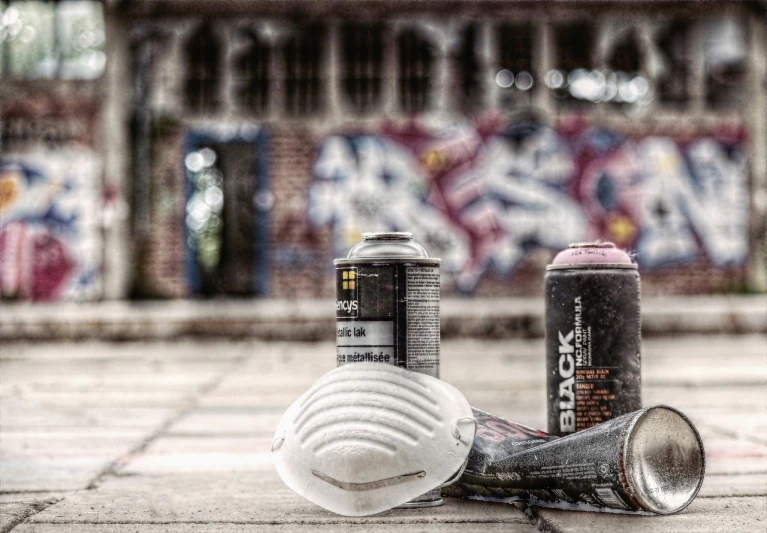a couple of spray cans sitting on top of a sidewalk, by Anton Graff, graffiti, shallow depth of field hdr 8 k, abandoned buildings, under repairs, white paint