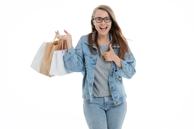 a woman holding shopping bags and giving a thumbs up, a stock photo, by Aleksander Gierymski, shutterstock, figuration libre, wearing a jeans jackets, girl with glasses, high quality product photo, with a white background