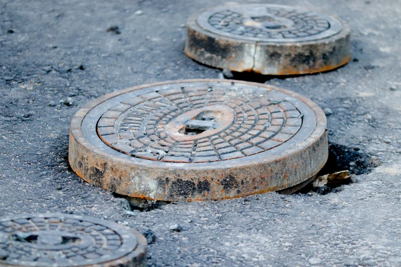 a close up of a manhole cover on the ground, a tilt shift photo, by Stefan Gierowski, shutterstock, mingei, under repairs, drainpipes, stock photo