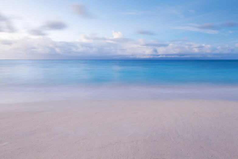 a large body of water sitting on top of a sandy beach, a picture, by Gawen Hamilton, minimalism, tropical ocean, blue soft light, calm clouds, white beaches