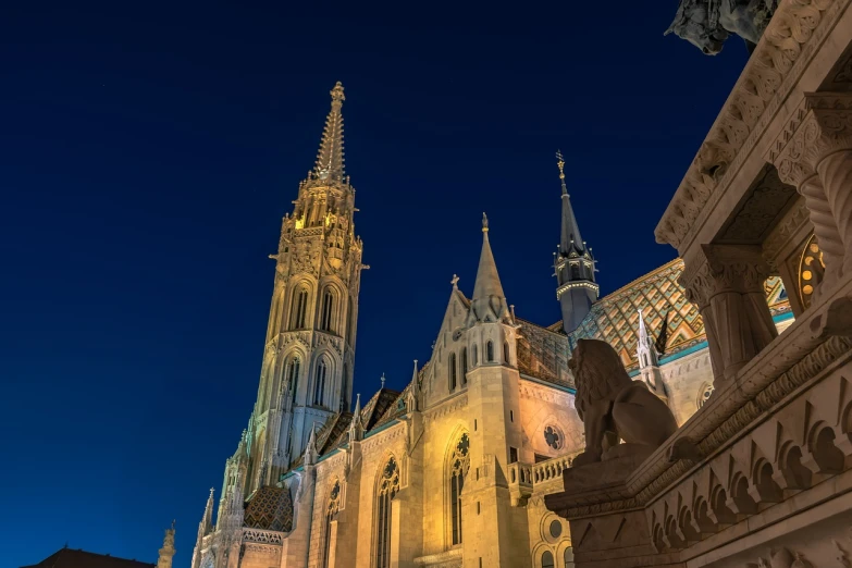a large cathedral is lit up at night, a photo, by Thomas Häfner, shutterstock, budapest, cinematic view from lower angle, jester, blonde