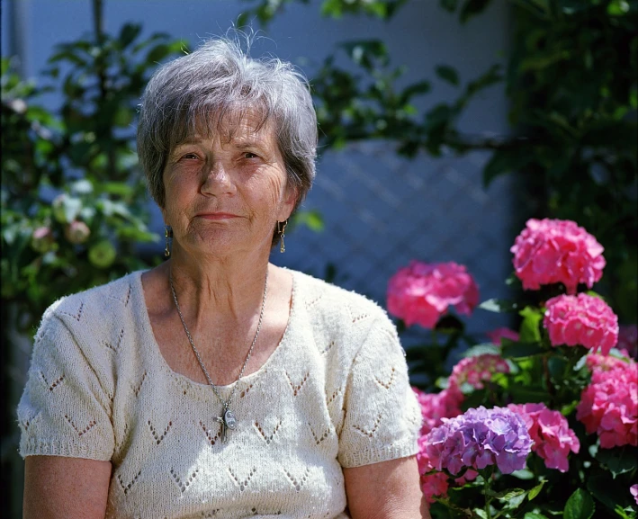 a woman sitting in front of a bunch of flowers, a portrait, dementia, taken in the 2000s, looking serious, silver