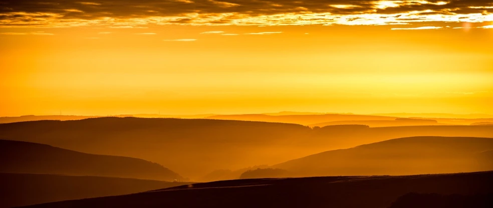 the sun is setting over the mountains in the distance, by Thomas Häfner, pexels, fine art, shades of yellow, yorkshire, flowing hills, telephoto shot