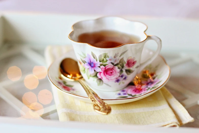 a cup of tea sitting on top of a saucer, a picture, by Rhea Carmi, pixabay, 🐝👗👾, flowery wallpaper, softly - lit, spoon