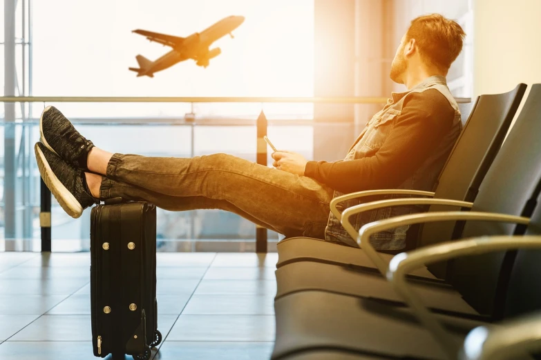 a man sitting in an airport waiting for a plane, a picture, shutterstock, beautiful background, stock photo, resting on his throne, in suitcase