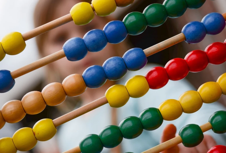 a close up of an abacuse with a child in the background, a picture, mathematics, beads, closeup photo