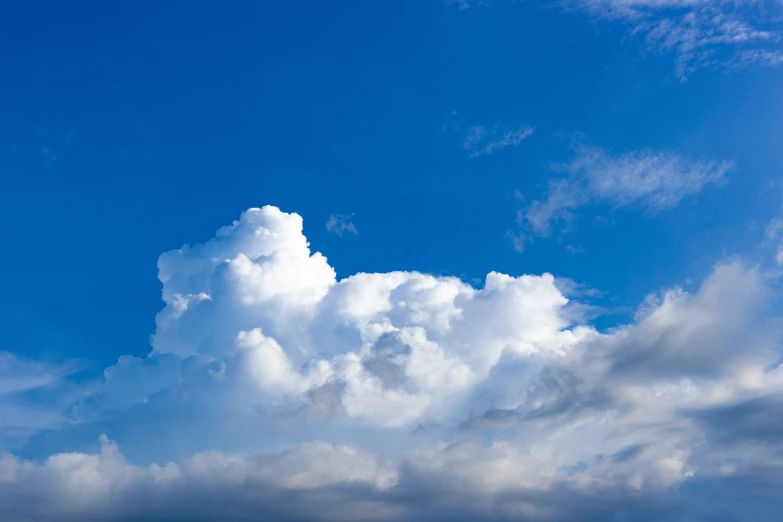 there is a plane that is flying in the sky, a stock photo, minimalism, giant cumulonimbus cloud, beautiful cloudy deep blue sky, vibrant blue sky background, in forcasted sky