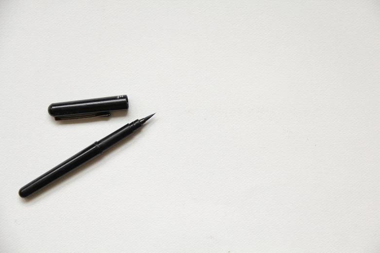 a black pen sitting on top of a white table, visual art, minimalist background, line brush, product introduction photo