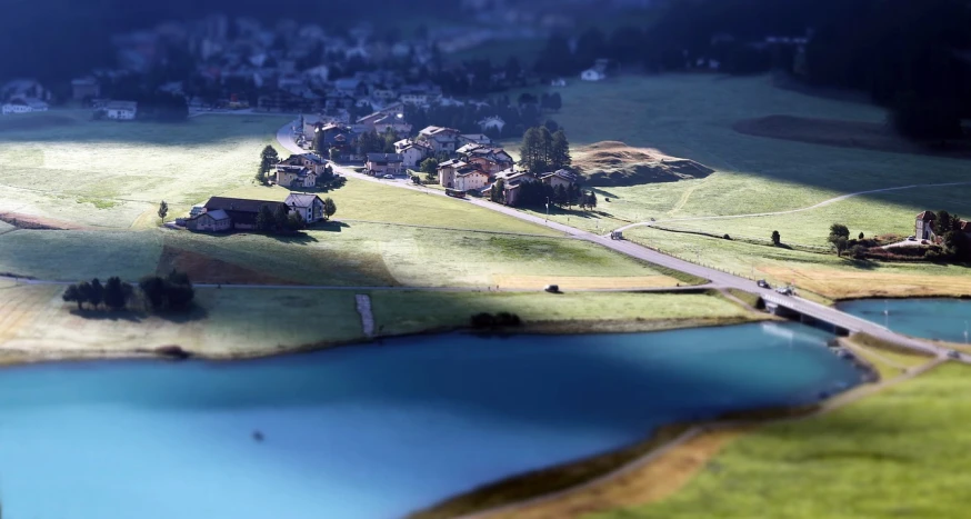 an aerial view of a small town next to a lake, a tilt shift photo, by Werner Andermatt, flickr, photorealism, morning detail, swiss, photorealism. trending on flickr, slice of life”