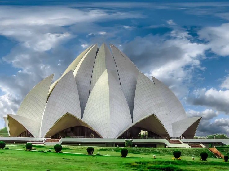 a large building sitting on top of a lush green field, inspired by Buckminster Fuller, shutterstock, indian temple, white sweeping arches, lotus, architecture photo