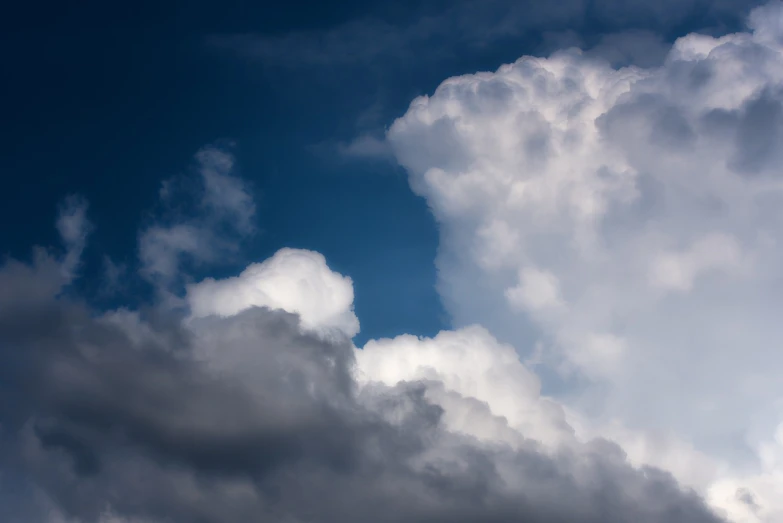 a plane flying through a cloudy blue sky, a stock photo, minimalism, background full of stormy clouds, white cyclops portrait in sky, cloud in the shape of a dragon, dark blue sky