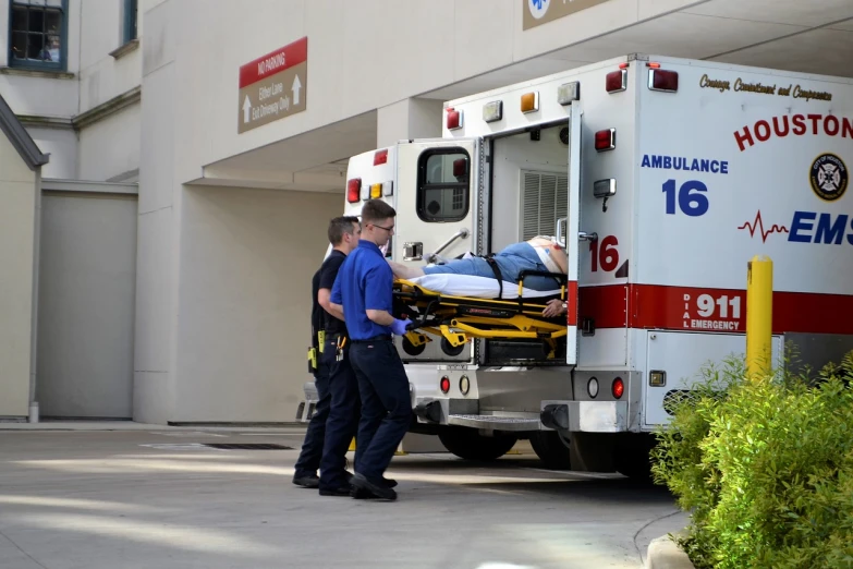 a man on a stretcher being loaded into an ambulance, a photo, istockphoto, wide shot photo, medical complex, tx