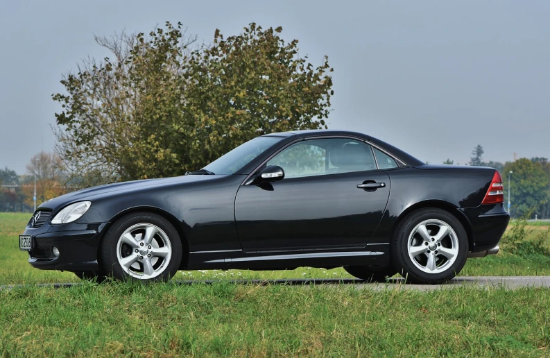 a black mercedes slk parked on the side of the road, a portrait, side elevation, commercial photograph, in a scenic background, prototype