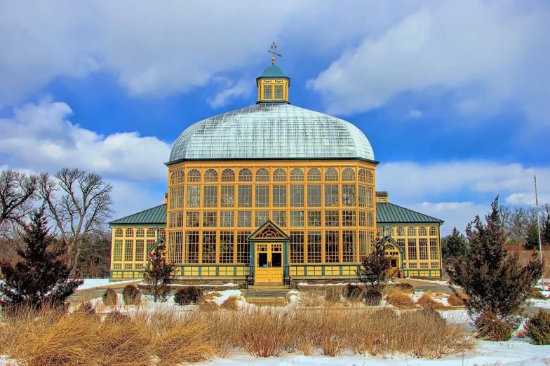 a large yellow building sitting on top of a snow covered field, a colorized photo, inspired by Edward Willis Redfield, pixabay contest winner, art nouveau, huge greenhouse, standing in a botanical garden, under glass dome, rhode island