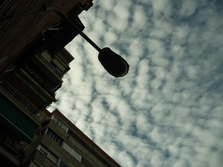 a street light hanging off the side of a building, inspired by André Kertész, flickr, happy clouds behind, madrid, extreme low angle, microphone silluette