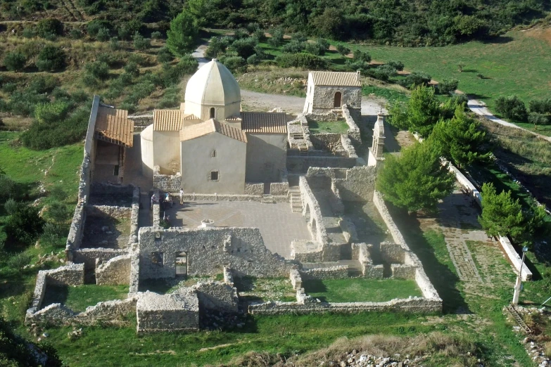 a large building sitting on top of a lush green hillside, inspired by Antonín Chittussi, flickr, romanesque, aerial view from above, destroyed church, pathos, the narthex