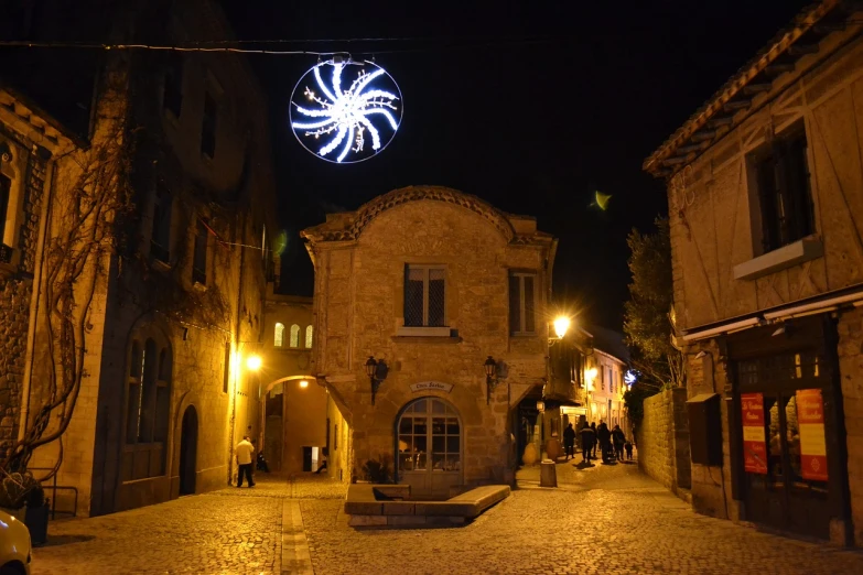 a clock that is on the side of a building, a photo, romanesque, festival. scenic view at night, tentacles climb from the portal, french village exterior, christmas night