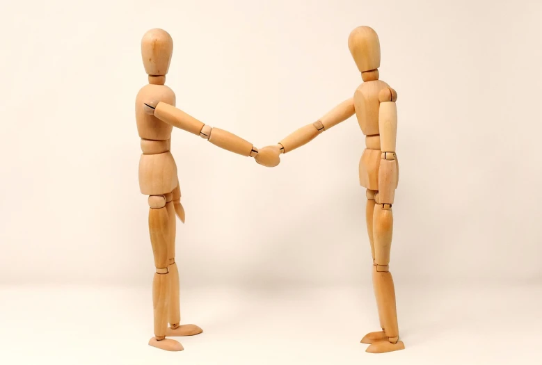 two wooden mannequins shaking hands against a white background, a picture, by Emma Andijewska, pexels, visual art, stick figures, istockphoto, holding court, hurt