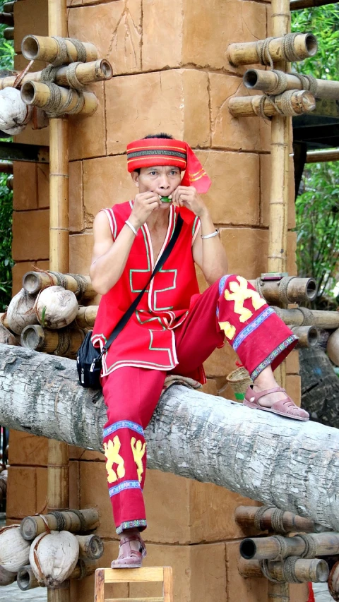 a man sitting on a log talking on a cell phone, inspired by Gong Xian, sumatraism, wearing red attire, tourist photo, there is a cigar in his mouth, asian woman