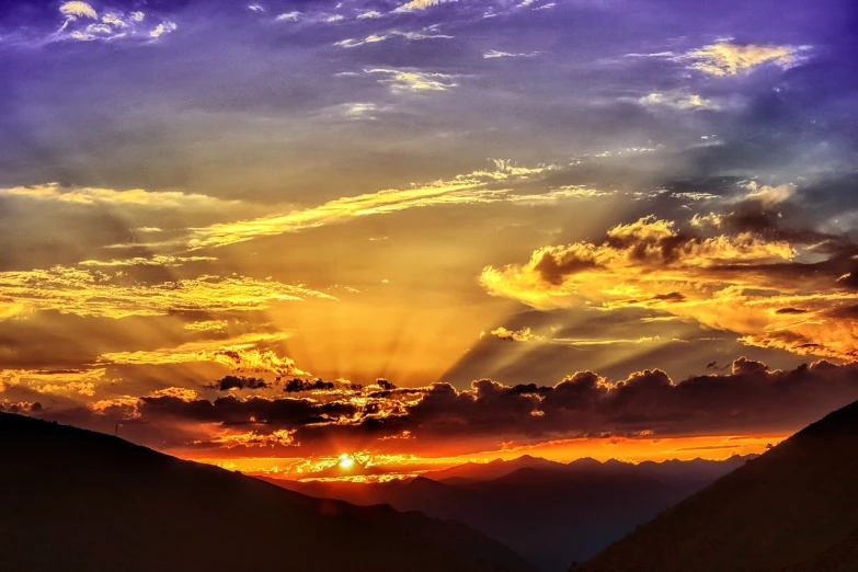 the sun is setting over a mountain range, by Tom Carapic, romanticism, beautiful light rays, vibrant sunset dramatic sky, violet and yellow sunset, sunburst