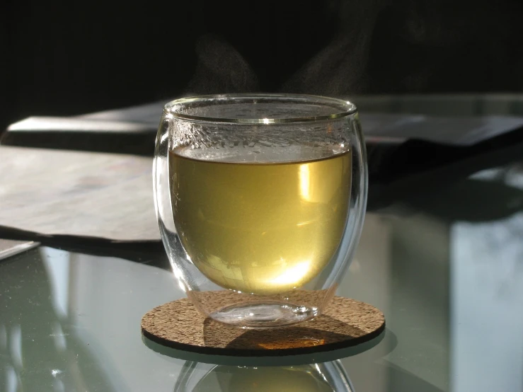 a glass of tea sitting on top of a glass table, flickr, golden mist, spherical, platinum, mead