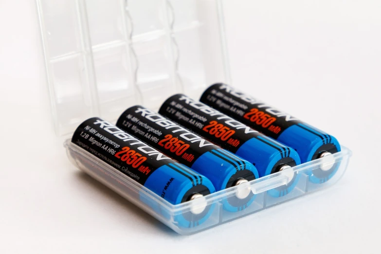 four batteries in a clear container on a white surface, a stock photo, by david rubín, blue rays, 1200 dpi, robin, closeup portrait