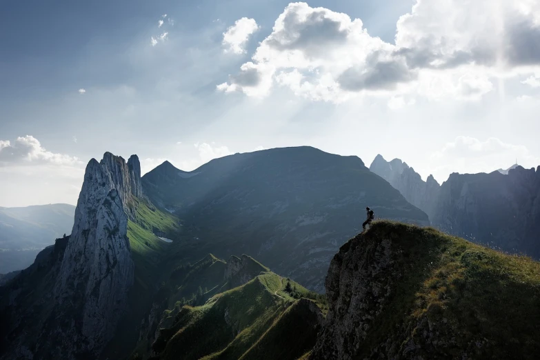 a person standing on top of a mountain, a picture, by Matthias Weischer, figuration libre, dolomites, very wide view, sunlit, cliffs