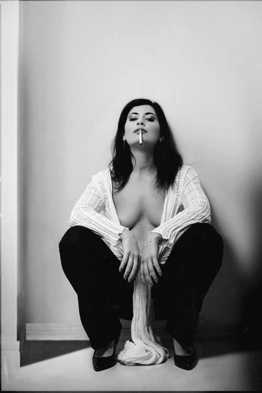 a black and white photo of a woman smoking a cigarette, a black and white photo, inspired by Marina Abramović, fine art, cleavage, dreamy mila kunis, kneeling, sexy pudica pose gesture