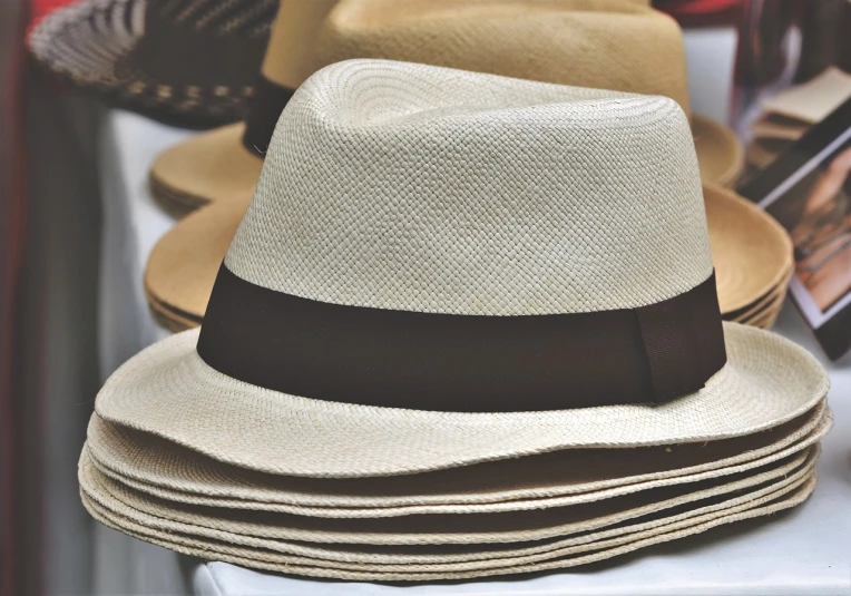a stack of hats sitting on top of a table, by Thomas Häfner, trimmed with a white stripe, istock, white straw flat brimmed hat, catalog photo