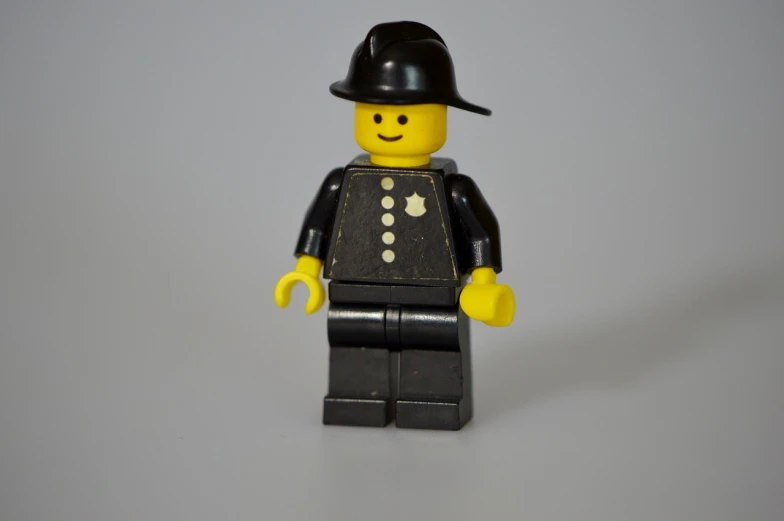 a close up of a lego man wearing a hat, a picture, figuration libre, policeman, museum quality photo, black, on a pale background