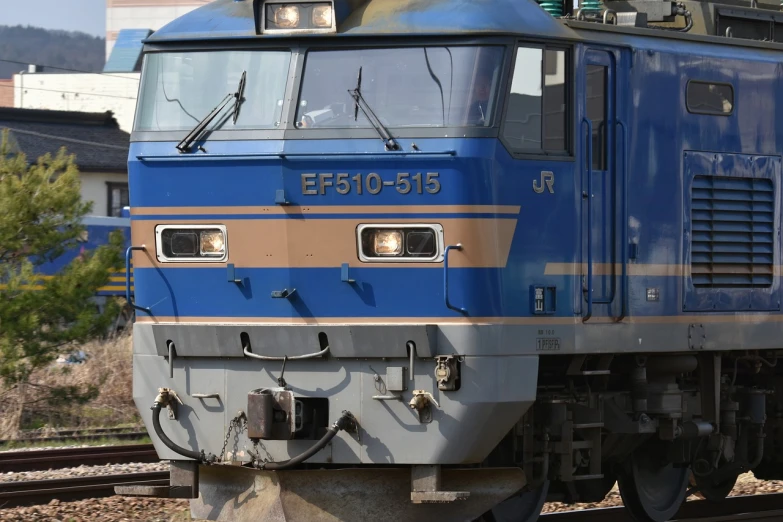 a blue train traveling down train tracks next to a tall building, shin hanga, real engine 5, closeup photo, european face, edo