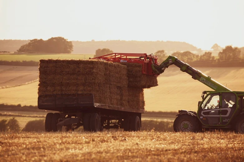 a tractor pulling a bale of hay in a field, shutterstock, crane shot, back - lit, organic biomass, hero shot