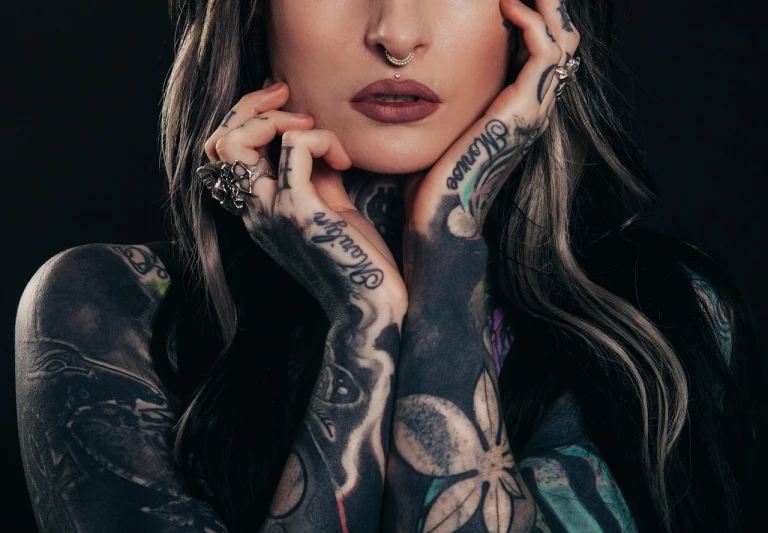 a woman with tattoos posing for a picture, by Emma Andijewska, close - up studio photo, hands on face, septum piercing, hands behind her pose!