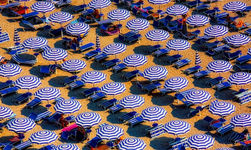 a beach filled with lots of blue and white umbrellas, a photo, by Richard Carline, precisionism, italy, in rich color, summer afternoon, vibrant patterns