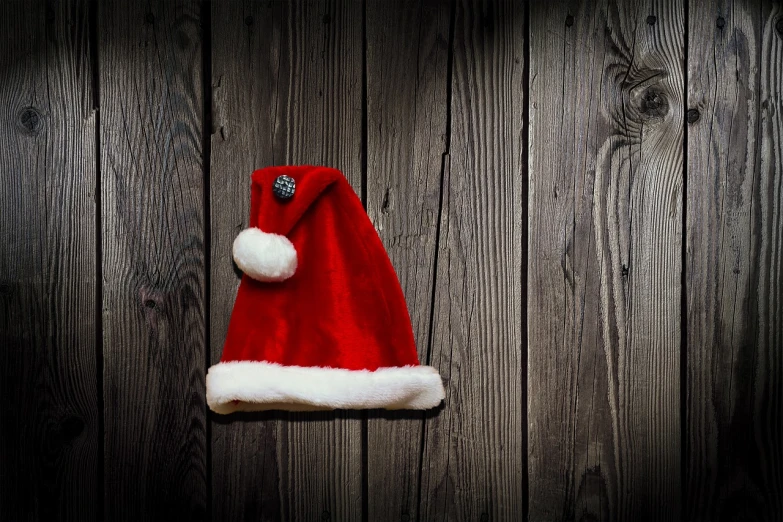 a red santa hat hanging on a wooden wall, a photo, pixabay, avatar image, handmade, a dark, family photo