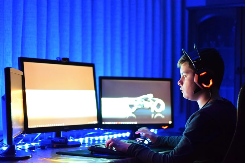 a boy sitting in front of two computer monitors, blue and orange lighting, game resources, centre image, edited