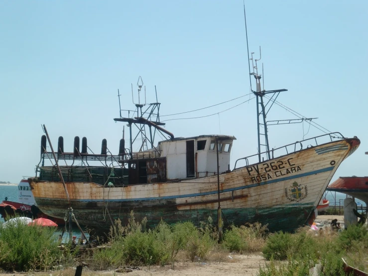 a boat sitting on top of a beach next to a body of water, a portrait, by Altichiero, flickr, hurufiyya, weathered olive skin, arizona, big graphic seiner ship, yard