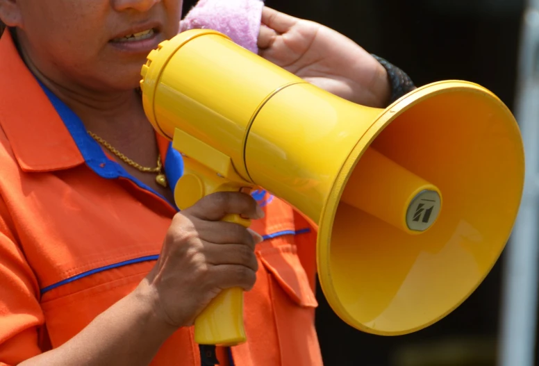 a man in an orange shirt holding a yellow megaphone, by Jan Rustem, shutterstock, hurufiyya, thailand, detailed zoom photo, a woman, politicians