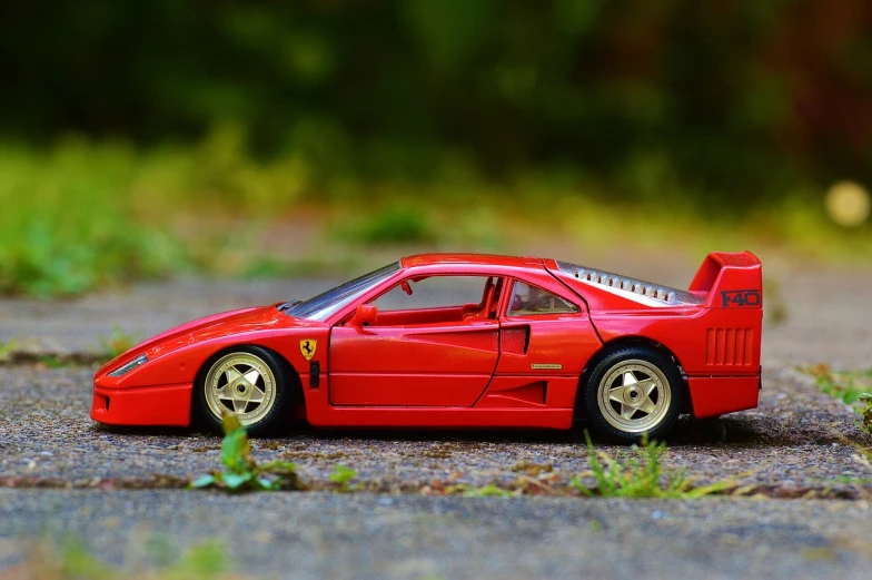 a red toy car sitting on top of a gravel road, inspired by Bernardo Cavallino, pexels contest winner, photorealism, ferrari f 4 0, side - view, miniature model, beautiful wallpaper