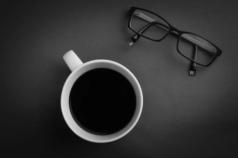a cup of coffee next to a pair of glasses, a black and white photo, by Andrei Kolkoutine, minimalism, wallpaper mobile, serious business, monochrome color, interesting angle