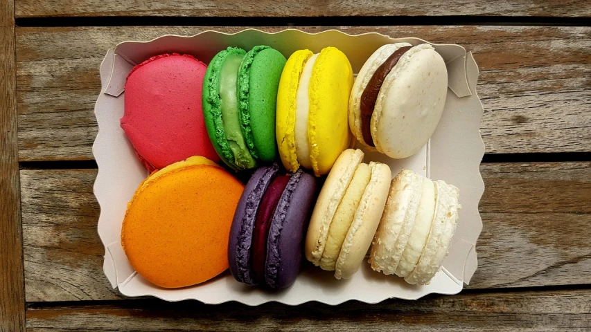 a box of macarons sitting on top of a wooden table, strong and vibrant colors, patron saint of 🛸🌈👩🏾, 8 x, colors white!!