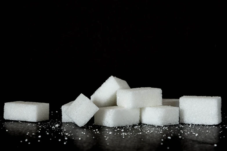 a pile of sugar cubes sitting on top of a table, by Adam Marczyński, in front of a black background, 💋 💄 👠 👗, sugar snow, obese