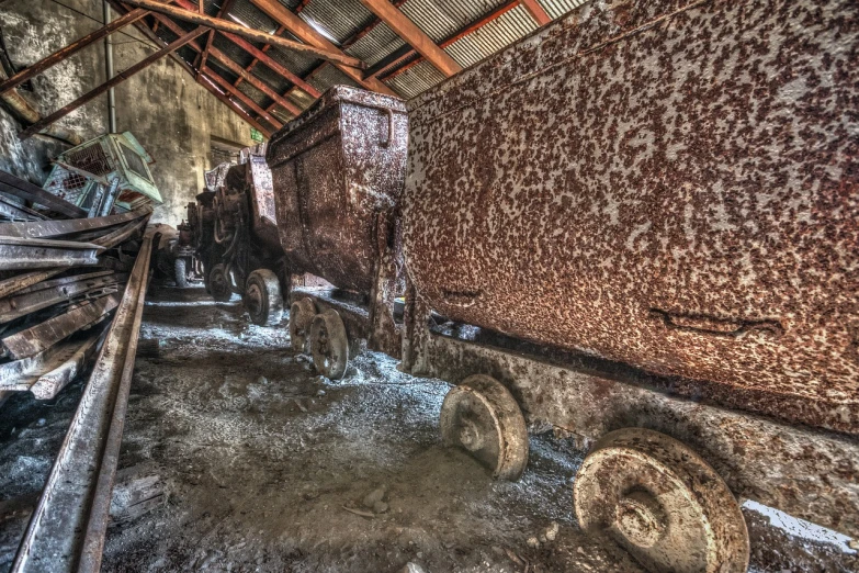 a train that is sitting inside of a building, by Raymond Normand, flickr, auto-destructive art, rusty vehicles, covered in salt, mine cart, 2 4 mm iso 8 0 0 color