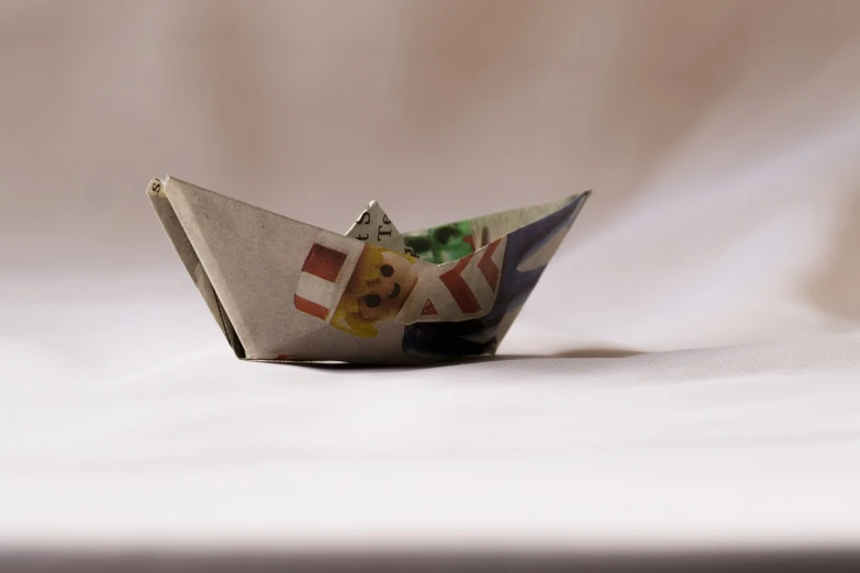 a paper boat sitting on top of a bed, a picture, by Aleksander Gierymski, poker, bowl, turnaround, dof