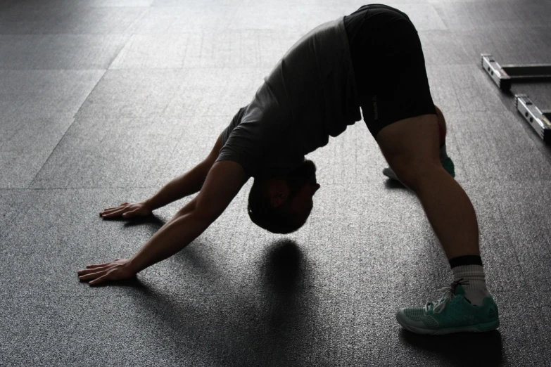 a man doing a handstand in a gym, a picture, pixabay, bending over, tail, face down, backlite