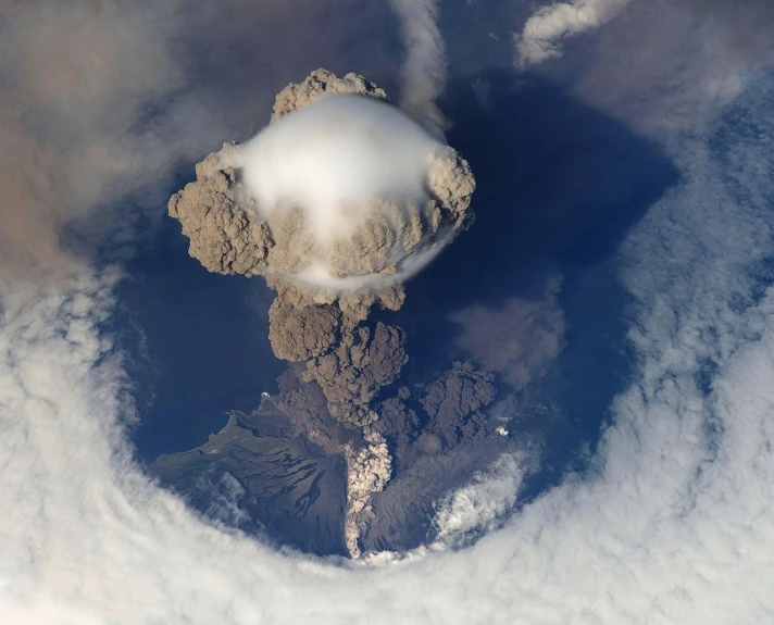 an aerial view of a volcano spewing smoke into the sky, by Alexander Scott, flickr, surrealism, photograph credit: ap, looming over earth, the cytoplasm”, viewed from bird's-eye