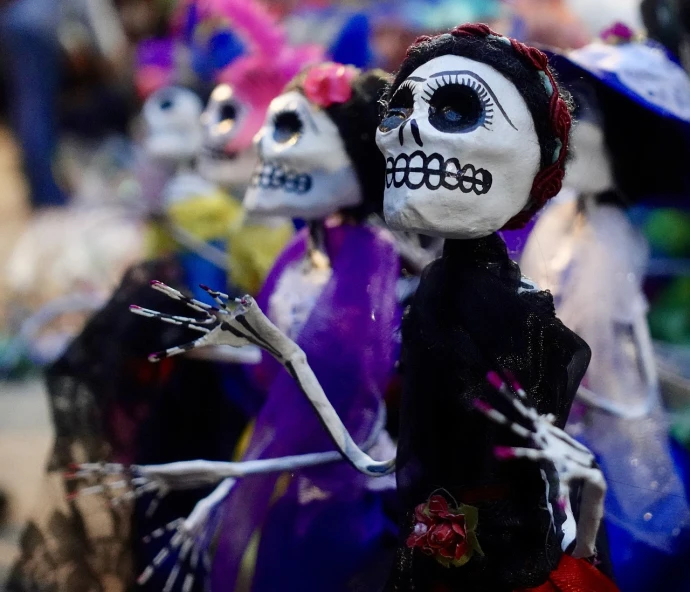 a group of skeleton figurines sitting next to each other, a portrait, parade, she is mexican, zoom shot, confetti