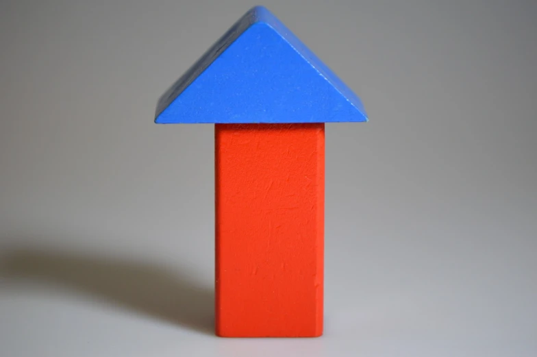 a red and blue block with a blue arrow, an abstract sculpture, inspired by Joel Shapiro, unsplash, simple gable roofs, 7 0 mm photo, colored accurately, top - side view