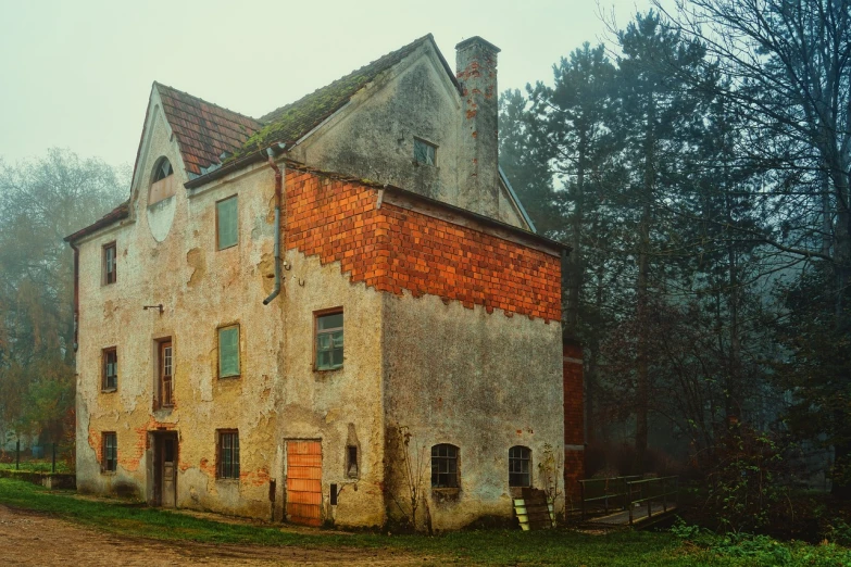 an old building sitting on the side of a dirt road, a photo, inspired by Gerard Soest, shutterstock, tonalism, mill, normal place with weird feeling, (((mist))), overcast weather